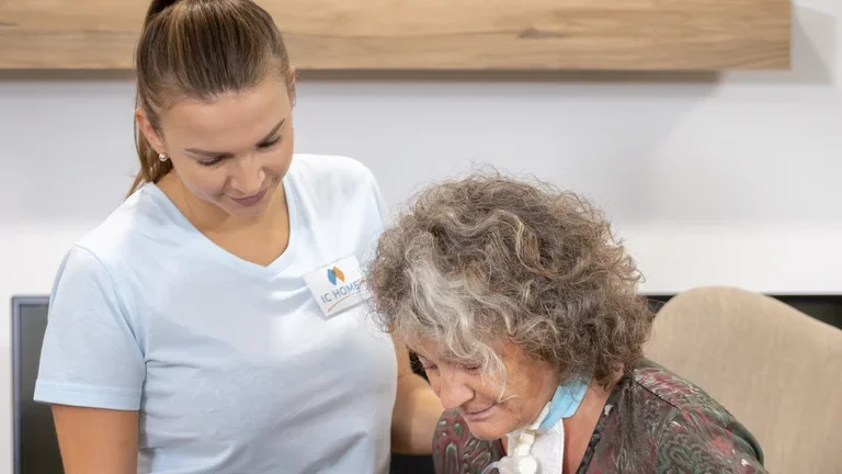 Eine Pflegerin steht neben einer Frau mit Rollator 