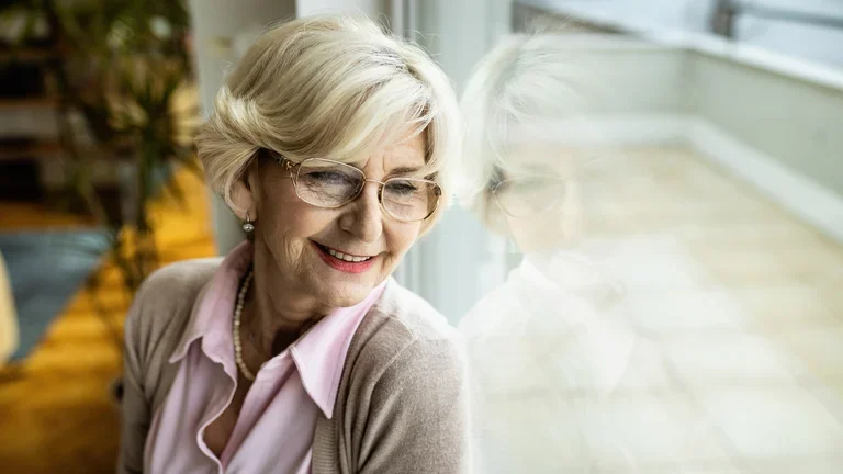 Eine Patientin, die zu Hause parenteral ernährt wird, sitzt am Fenster und genießt ihre Freiheiten dank der heimparenteralen Ernährung.