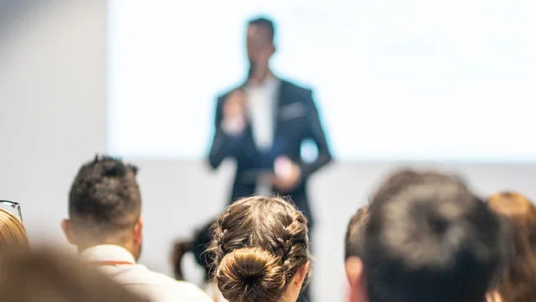 Eine vortragende Person steht vor sitzendem Publikum