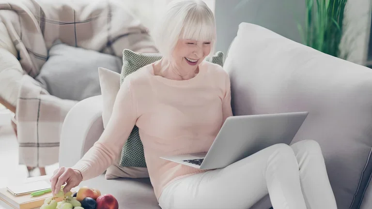 Seniorin schaut begeistert einen Film am Laptop