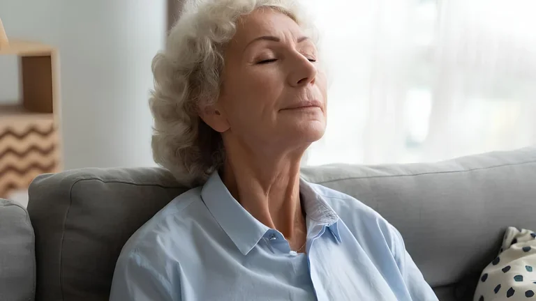 Seniorin macht Atemübung mit geschlossenen Augen