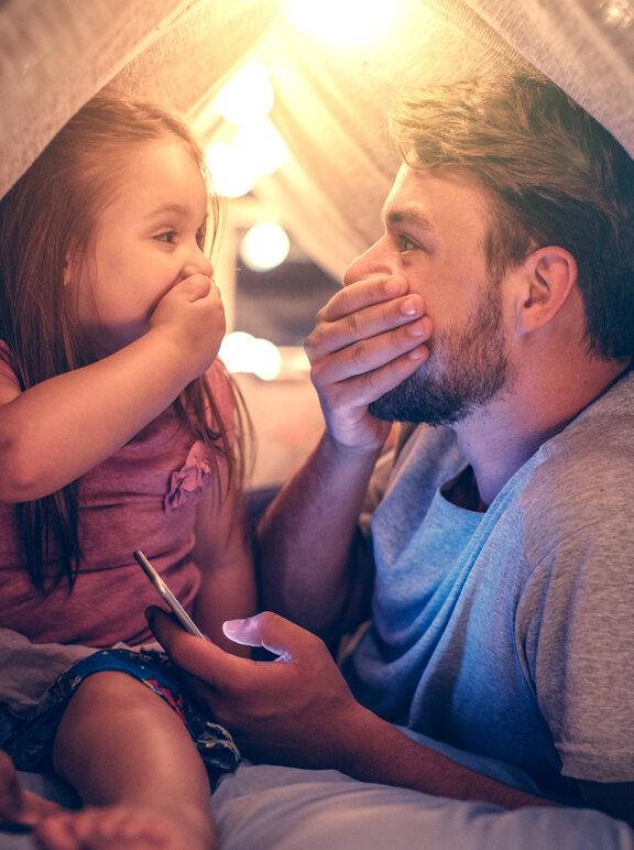 Papa spielt mit Tochter im Tipi im Wohnzimmer