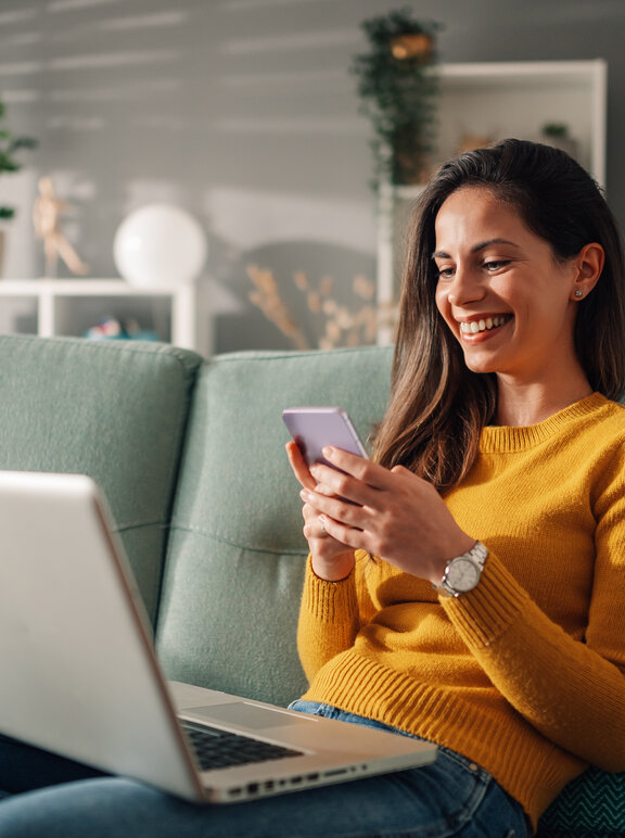 Frau sitzt am Laptop und Handy