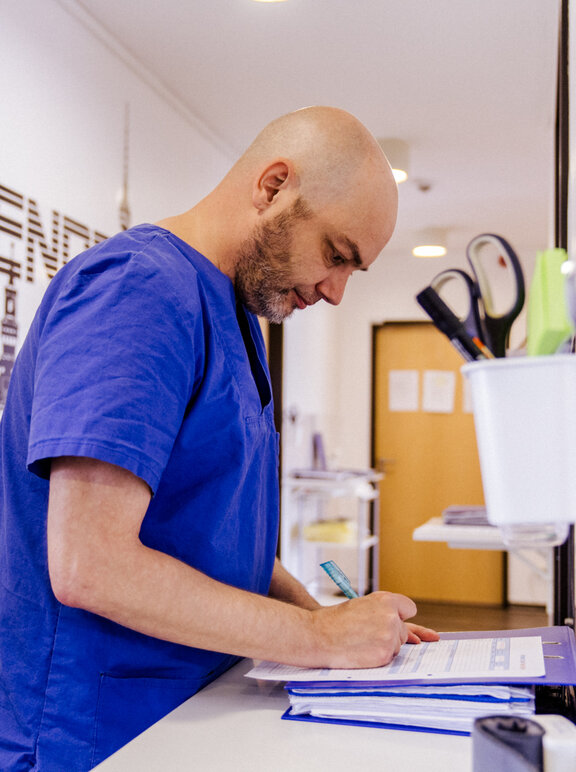 Pfleger schreibt auf einem Klemmbrett 