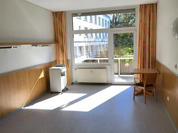 Bewohnerzimmer mit Tisch und Stuhl und einem Balkon