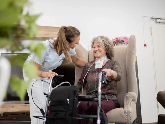 Pflegerin mit Patientin im Wohnraum 
