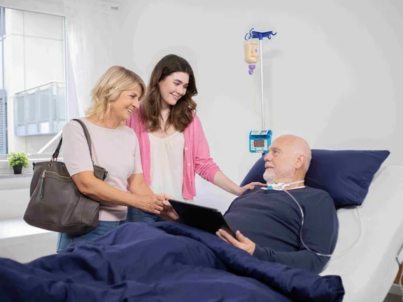 Zwei Frauen stehen am Bett eines Patienten in einer Intensivpflege-WG