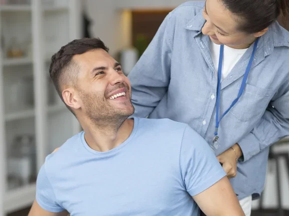 Eine Pflegerin schiebt einen Mann im Rollstuhl zuhause