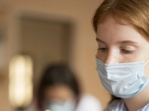 Frau mit Mundschutz desinfiziert ihren Finger