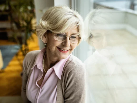 Eine Patientin, die zu Hause parenteral ernährt wird, sitzt am Fenster und genießt ihre Freiheiten dank der heimparenteralen Ernährung.