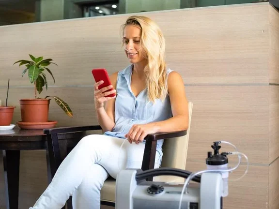 Junge Frau am Handy mit Beatmungsgerät