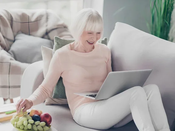 Seniorin schaut begeistert einen Film am Laptop