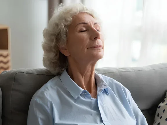 Seniorin macht Atemübung mit geschlossenen Augen