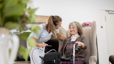 Pflegerin mit Patientin im Wohnraum 