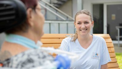 Pflegerin im Garten mit Patientin