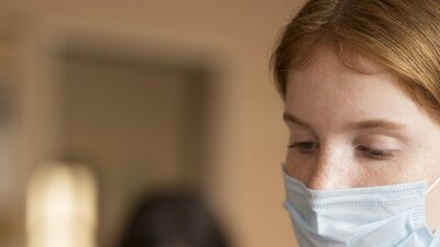 Frau mit Mundschutz desinfiziert ihren Finger