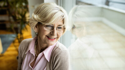 Eine Patientin, die zu Hause parenteral ernährt wird, sitzt am Fenster und genießt ihre Freiheiten dank der heimparenteralen Ernährung.