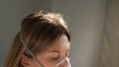 Eine junge Frau atmet in eine Atemmaske