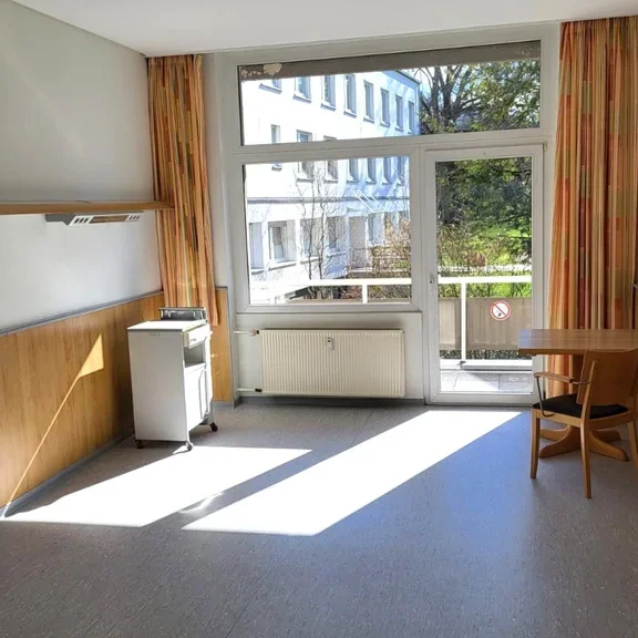 Bewohnerzimmer mit Tisch und Stuhl und einem Balkon