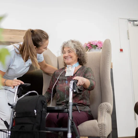 Pflegerin mit Patientin im Wohnraum 