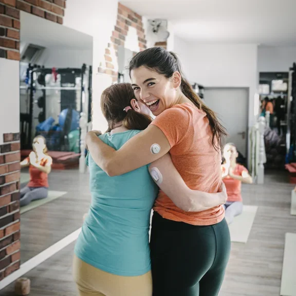 Diabetes Patientinnen mit Sensoren Arm in Arm im Fitnessstudio