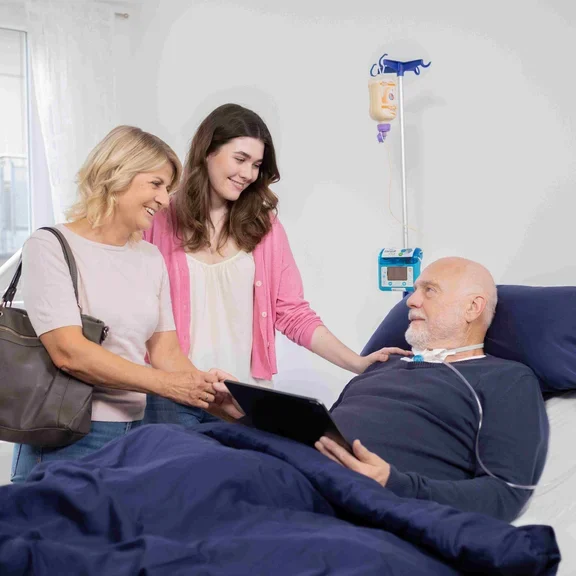 Zwei Frauen stehen am Bett eines Patienten in einer Intensivpflege-WG