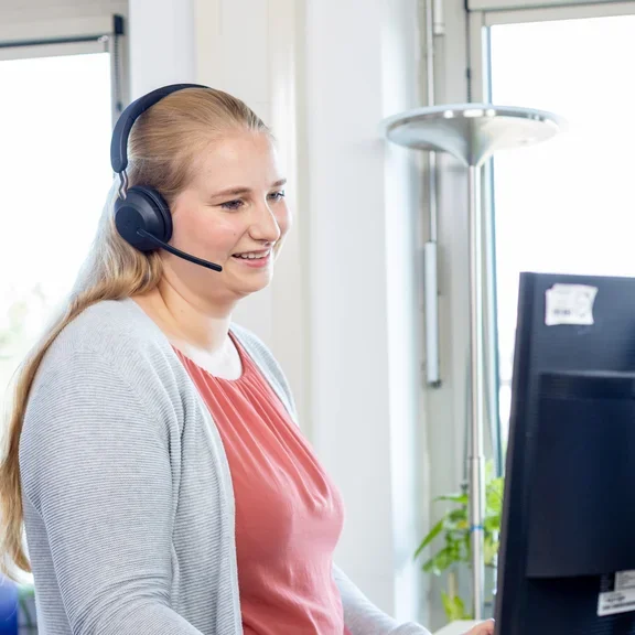 Eine Frau steht im Büro an einem Schreibtisch