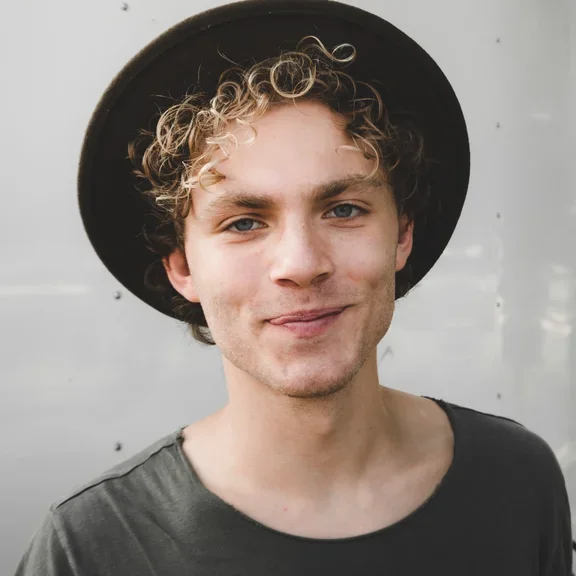 Ein Mann mit Hut schaut in die Kamera. 