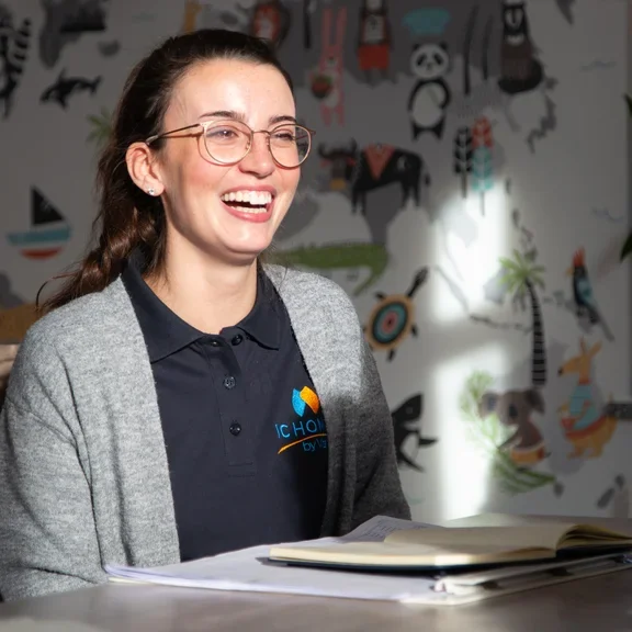 Eine Pflegefachkraft sitzt am Tisch und lacht