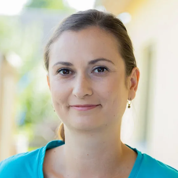 Eine Pflegerin lächelt freundlich zurückhaltend in die Kamere 