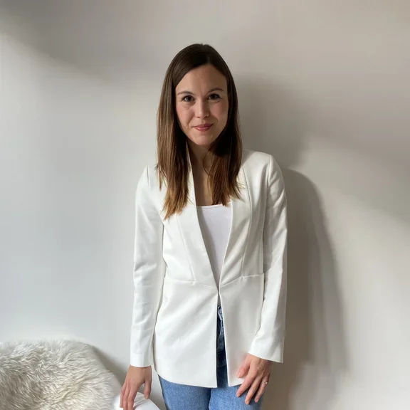 Eine Frau steht neben einem Stuhl auf dem ein Laptop und ein Notizbuch liegen