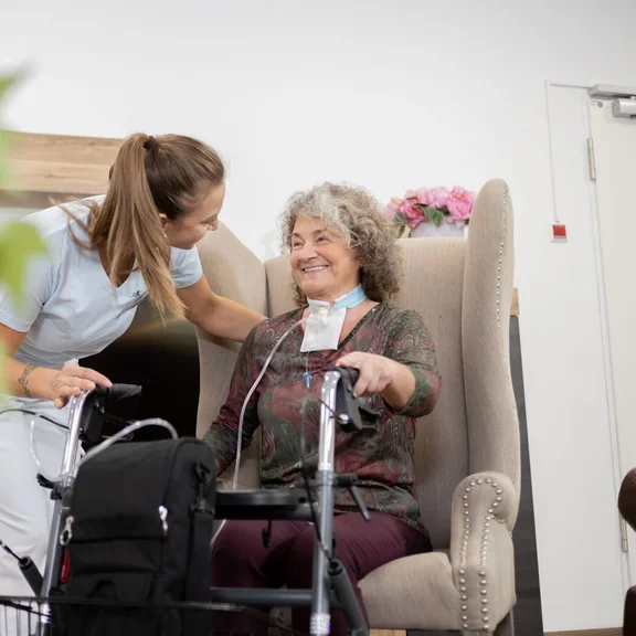 Pflegerin mit Patientin im Wohnraum 